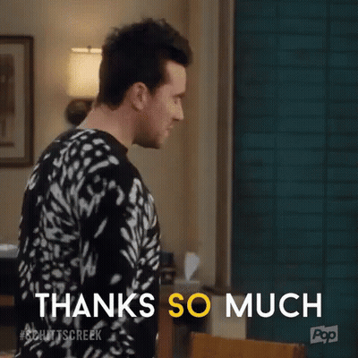 A Man In A Black And White Sweater Is Standing In A Living Room . GIF