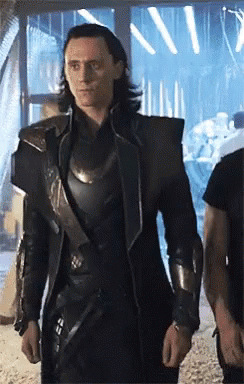 A Man In A Black Armored Suit Is Standing In A Room . GIF