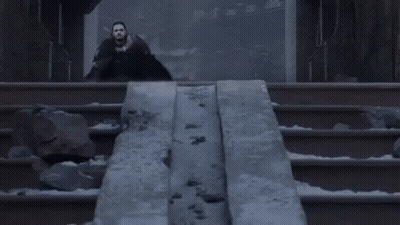 A Man In A Black Cape Is Standing In Front Of A Statue Of A Dragon . GIF