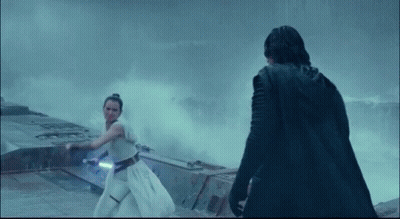 A Man In A Black Cape Stands Next To A Woman Holding A Light Saber GIF