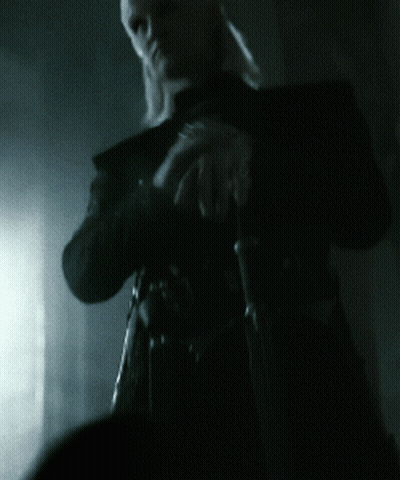 A Man In A Black Coat Holds A Sword In His Hands GIF