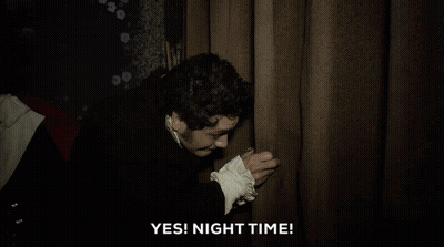A Man In A Black Coat Is Holding A Curtain And Saying Yes ! Night Time . GIF