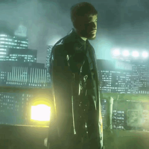 A Man In A Black Coat Is Holding A Gun In Front Of A City Skyline GIF
