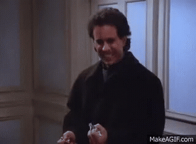 A Man In A Black Coat Is Holding Two Keys In His Hands And Smiling . GIF