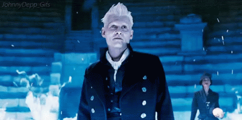 A Man In A Black Coat Is Standing In A Dark Room Looking Up At Something . GIF