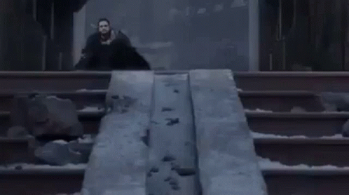 A Man In A Black Coat Is Standing Next To A Statue Of A Dragon . GIF