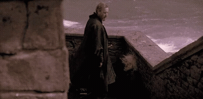 A Man In A Black Coat Is Walking Down Stairs . GIF
