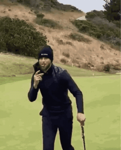 A Man In A Black Hat Is Holding A Golf Club On A Golf Course . GIF