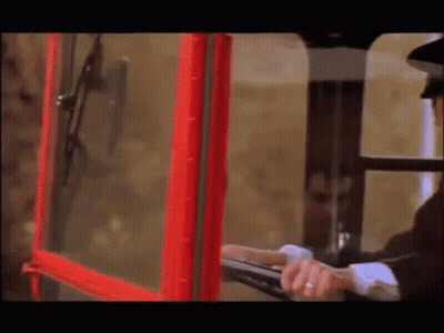 A Man In A Black Hat Is Looking Out Of A Red Telephone Booth GIF