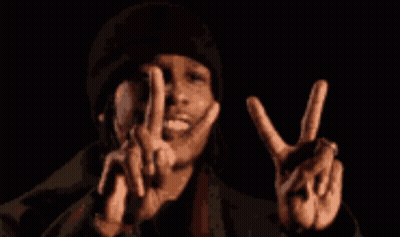 A Man In A Black Hat Is Making A Peace Sign With His Hands GIF