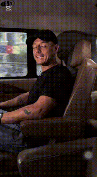 A Man In A Black Hat Is Sitting In The Back Seat Of A Car . GIF