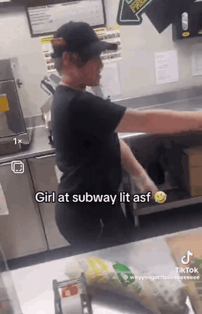 A Man In A Black Hat Is Standing In A Kitchen Behind A Counter With A Sign That Says Girl At Subway Lit Asf GIF