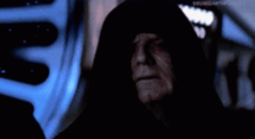 A Man In A Black Hood Is Standing In A Dark Room With A Starry Sky In The Background . GIF