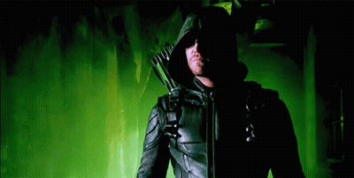 A Man In A Black Hooded Jacket Is Holding A Green Arrow GIF