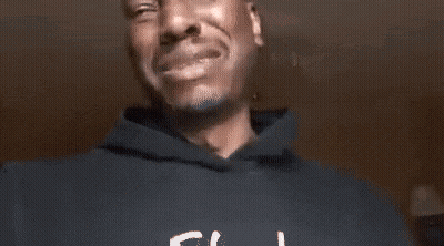 A Man In A Black Hoodie Is Crying While Holding His Hands To His Chest . GIF