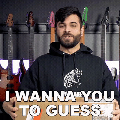 A Man In A Black Hoodie Is Holding A Cardboard Box That Says I Wanna You To Guess GIF