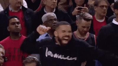 A Man In A Black Hoodie Is Standing In Front Of A Crowd Of People . GIF