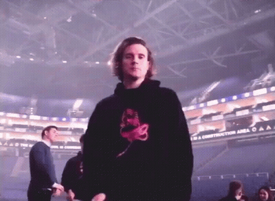 A Man In A Black Hoodie Is Standing In Front Of A Sign That Says To A Construction Area GIF
