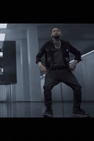 A Man In A Black Jacket And Black Pants Is Dancing In A Dark Room GIF