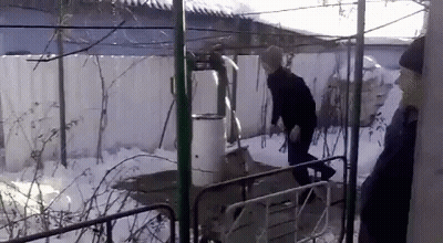 A Man In A Black Jacket And Hat Is Standing In The Snow GIF