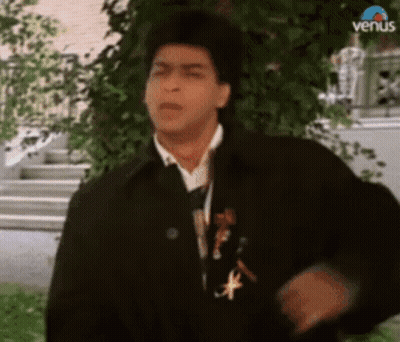 A Man In A Black Jacket And Tie Is Standing In Front Of A Tree And Stairs . GIF