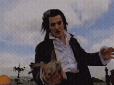 A Man In A Black Jacket And White Shirt Holds A Rabbit In His Hands GIF