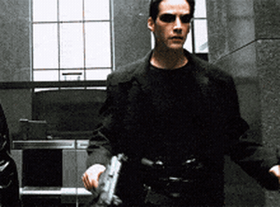 A Man In A Black Jacket Holds A Gun GIF