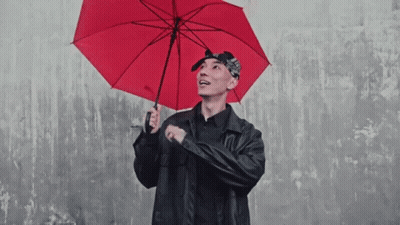 A Man In A Black Jacket Holds A Red Umbrella That Says ' Umbrella ' On It GIF