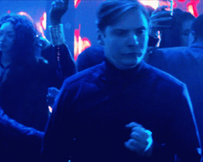 A Man In A Black Jacket Is Dancing In A Dark Room GIF