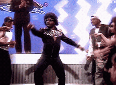 A Man In A Black Jacket Is Dancing In Front Of A Crowd With The Word Diversity In The Background GIF