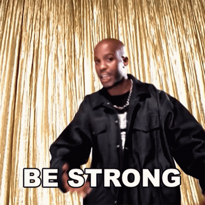 A Man In A Black Jacket Is Dancing In Front Of A Gold Curtain And Says Be Strong GIF