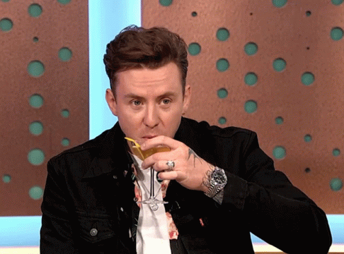 A Man In A Black Jacket Is Drinking A Drink GIF
