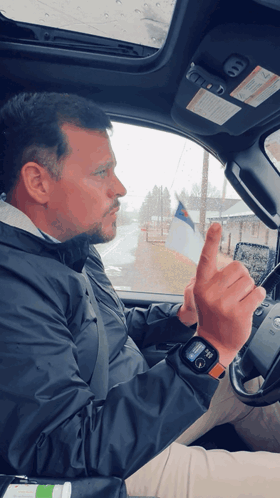 A Man In A Black Jacket Is Driving A Car And Giving A Middle Finger GIF