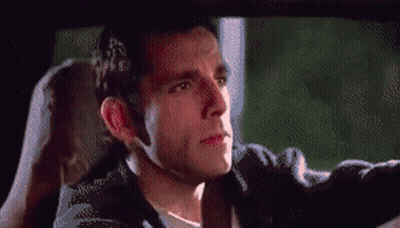 A Man In A Black Jacket Is Driving A Car And Looking Out The Window GIF