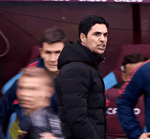 A Man In A Black Jacket Is Giving A Thumbs Up In Front Of A Banner That Says Cazoo GIF