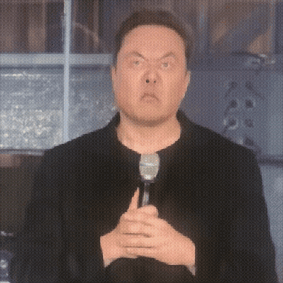 A Man In A Black Jacket Is Holding A Microphone GIF