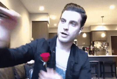 A Man In A Black Jacket Is Holding A Red Rose In His Hands GIF