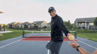 A Man In A Black Jacket Is Holding A Tennis Ball GIF