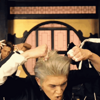 A Man In A Black Jacket Is Holding His Hair In A Circle GIF