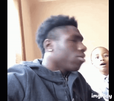A Man In A Black Jacket Is Making A Funny Face While A Boy Looks On GIF
