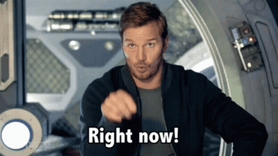 A Man In A Black Jacket Is Pointing At The Camera And Saying Right Now GIF