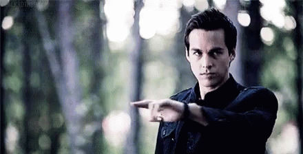A Man In A Black Jacket Is Pointing His Finger At Something In The Woods . GIF