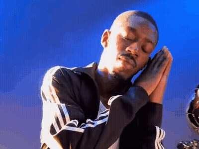 A Man In A Black Jacket Is Praying With His Hands Folded . GIF