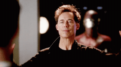 A Man In A Black Jacket Is Raising His Hands In The Air . GIF