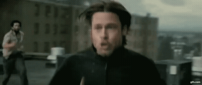 A Man In A Black Jacket Is Running On A Rooftop While Another Man Looks On . GIF