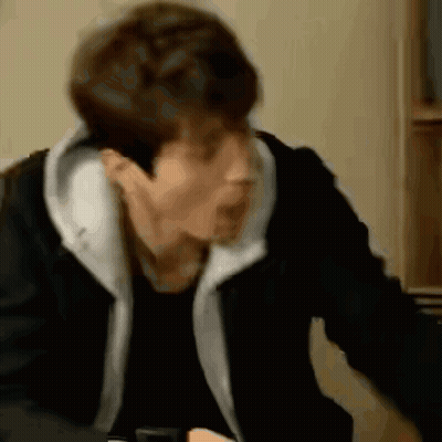 A Man In A Black Jacket Is Sitting At A Table With His Mouth Open . GIF