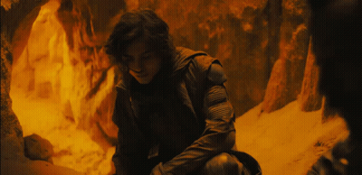 A Man In A Black Jacket Is Sitting In A Dark Cave GIF