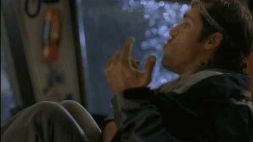 A Man In A Black Jacket Is Sitting On A Bus And Looking Out The Window . GIF