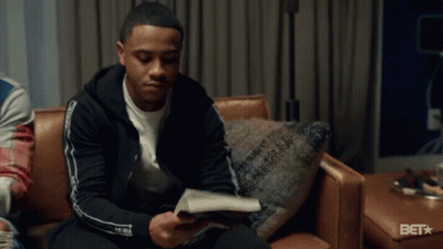 A Man In A Black Jacket Is Sitting On A Couch In A Room . GIF