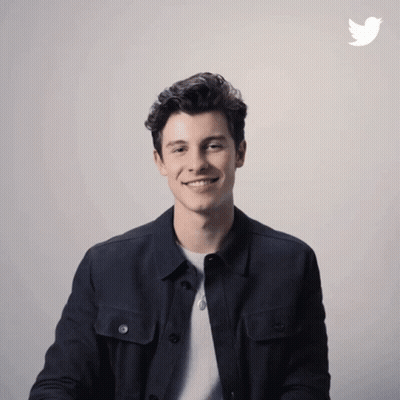 A Man In A Black Jacket Is Smiling In Front Of A Twitter Icon GIF